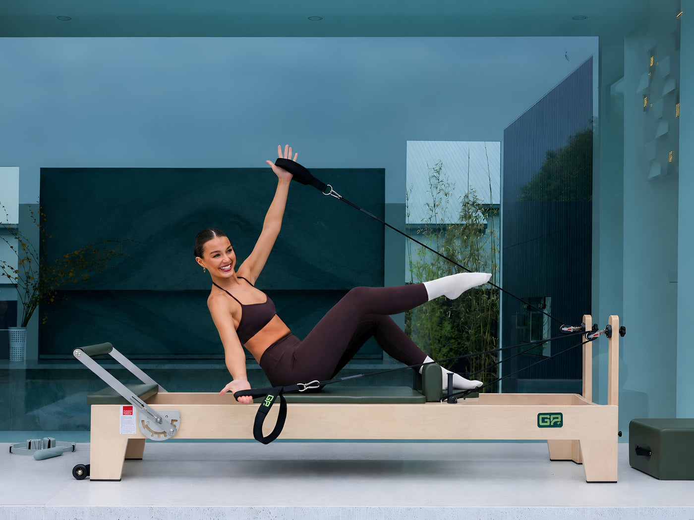 Woman exercising on a Pilates reformer machine in a modern studio.