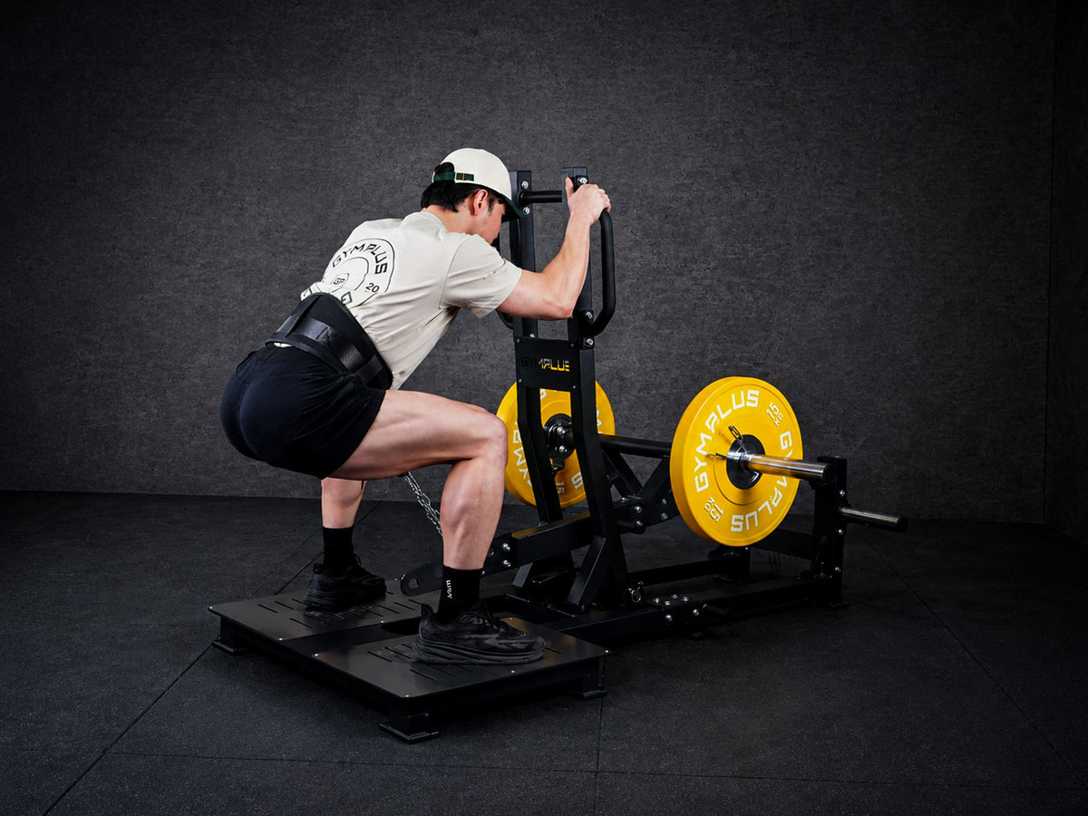 Gym Plus Belt Squat Machine - Plate Loaded BELT-SQUAT-01 a man performing belt squat with yellow bumper plates