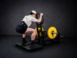 Gym Plus Belt Squat Machine - Plate Loaded BELT-SQUAT-01 a man performing belt squat with yellow bumper plates