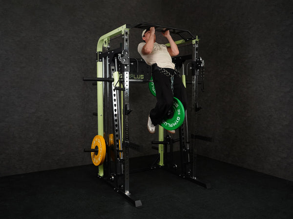 Gym Plus Power Dip Belt POWERBELT a man performing pull up using the dip belt with green bumper plates
