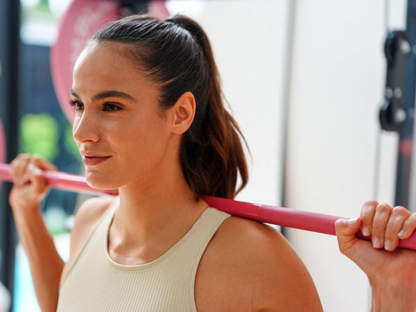 Gym Plus Cerakote Olympic Barbell - 15KG (Pink) GP-DOM-PINK-15KG woman smiling confidently while weight lifting