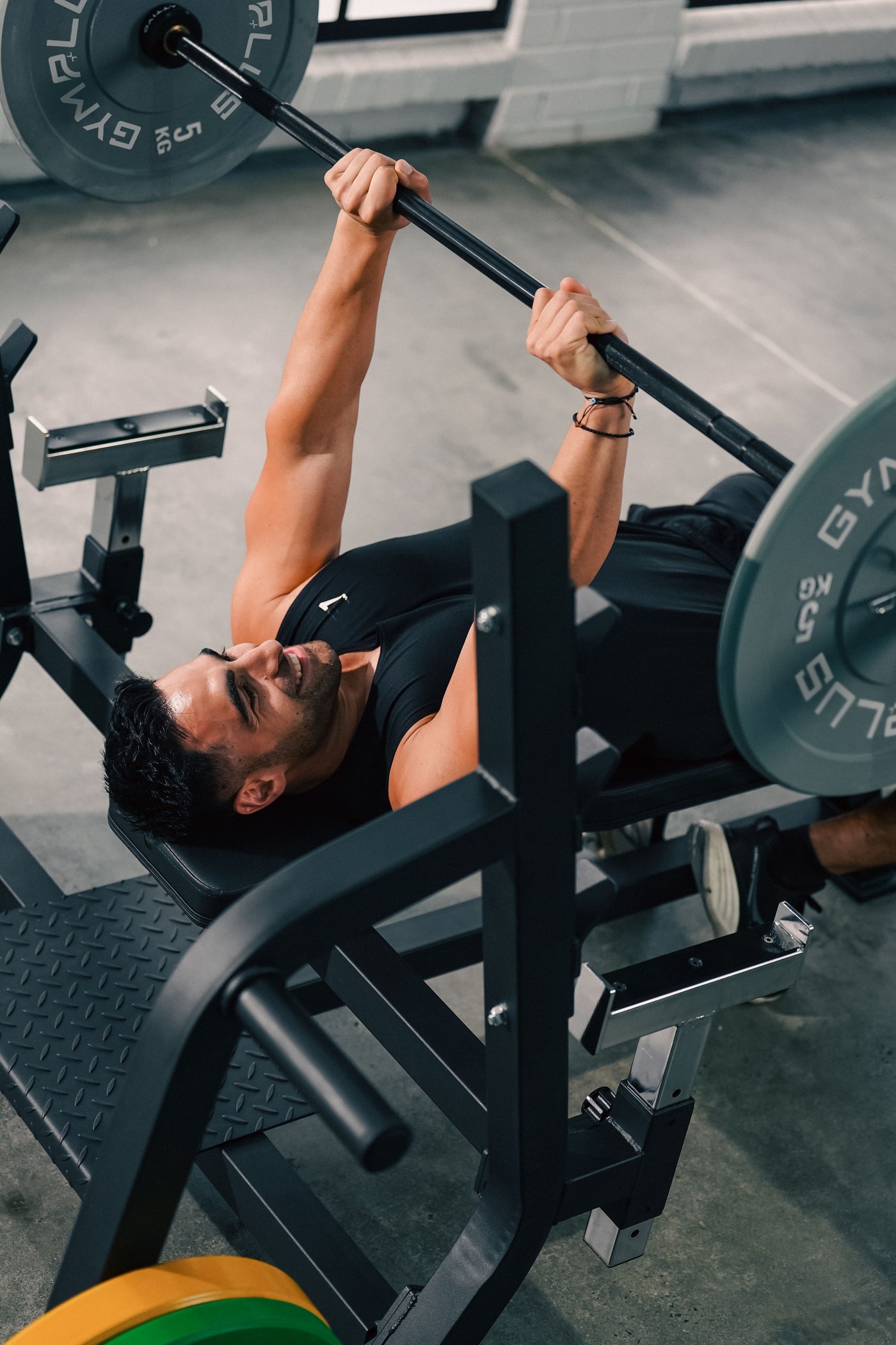 Man performing a barbell bench press in a gym setting