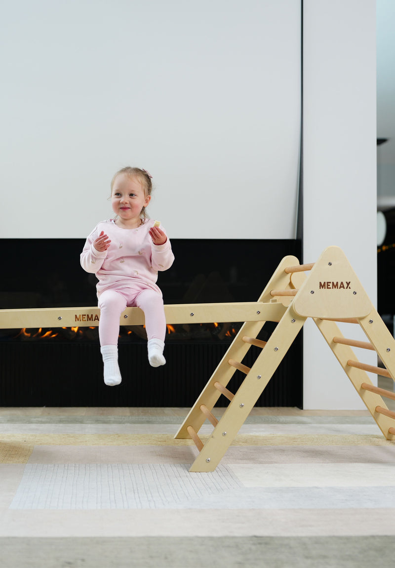 A toddler sitting on the Pikler Jungle Climbing Play Set