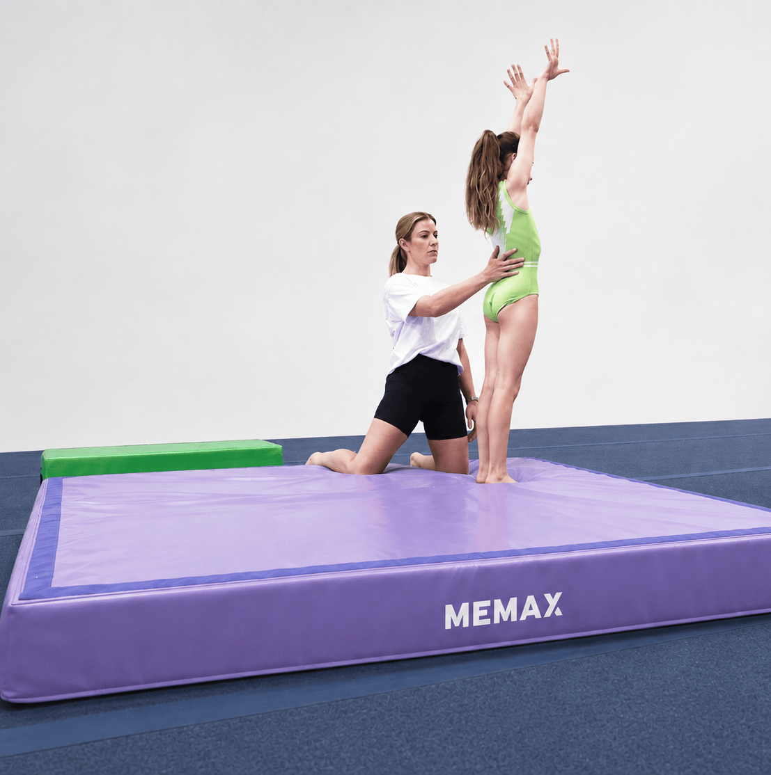 A girl and her coach doing gymnastics on the MEMAX Modular Landing Mat in purple