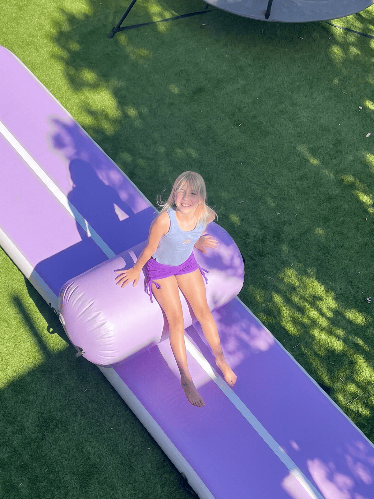 A girl looking upwards on a MEMAX Inflatable Air Track Mat in purple